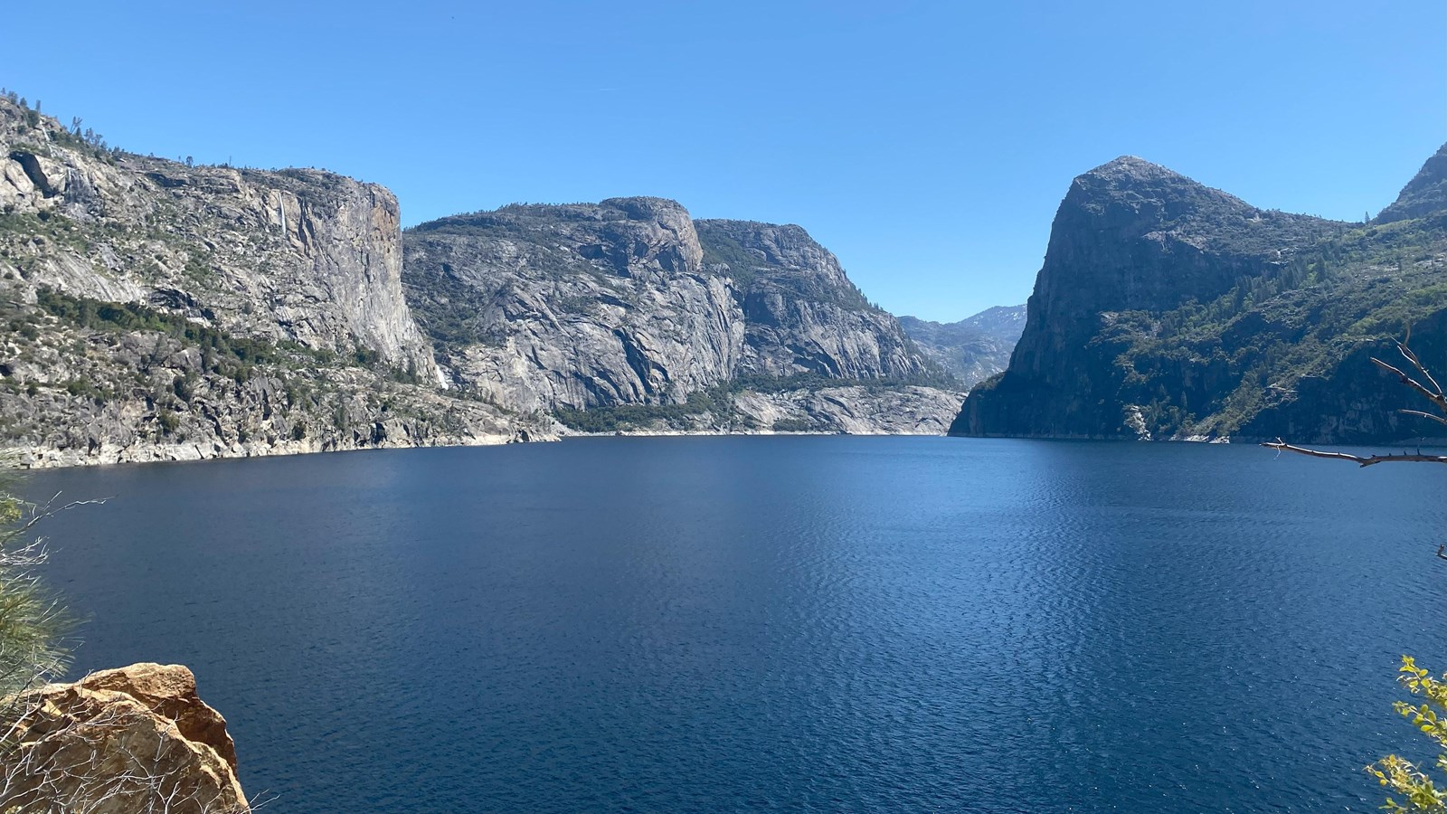 A vast blue reservoir surrounded by granite peaks