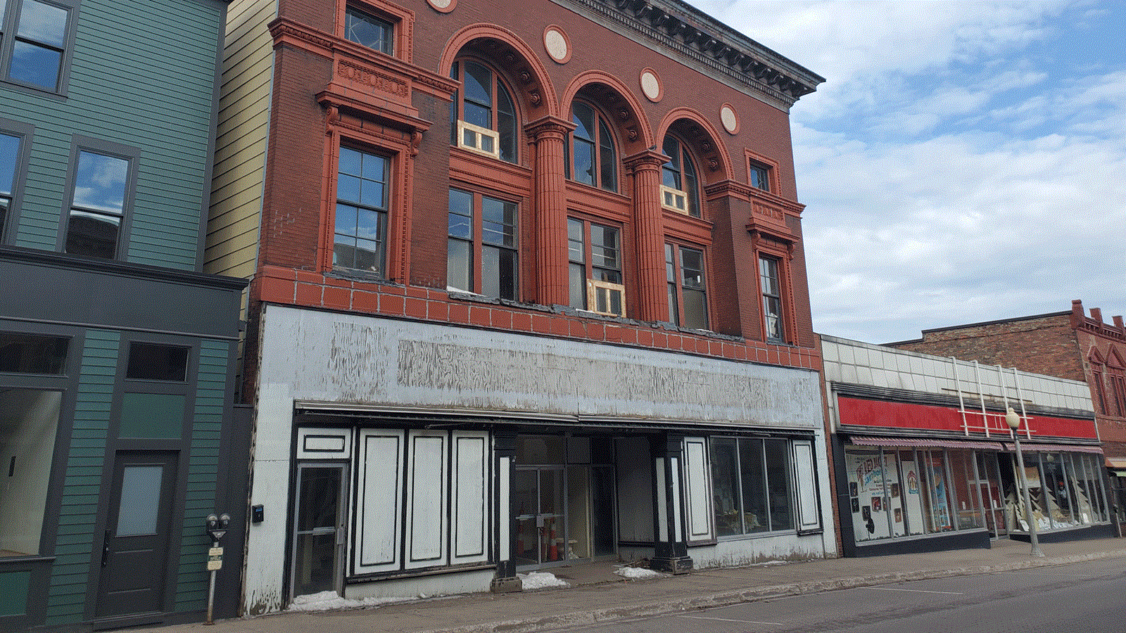 Three story building with brick front façade and yellow siding along the sides.