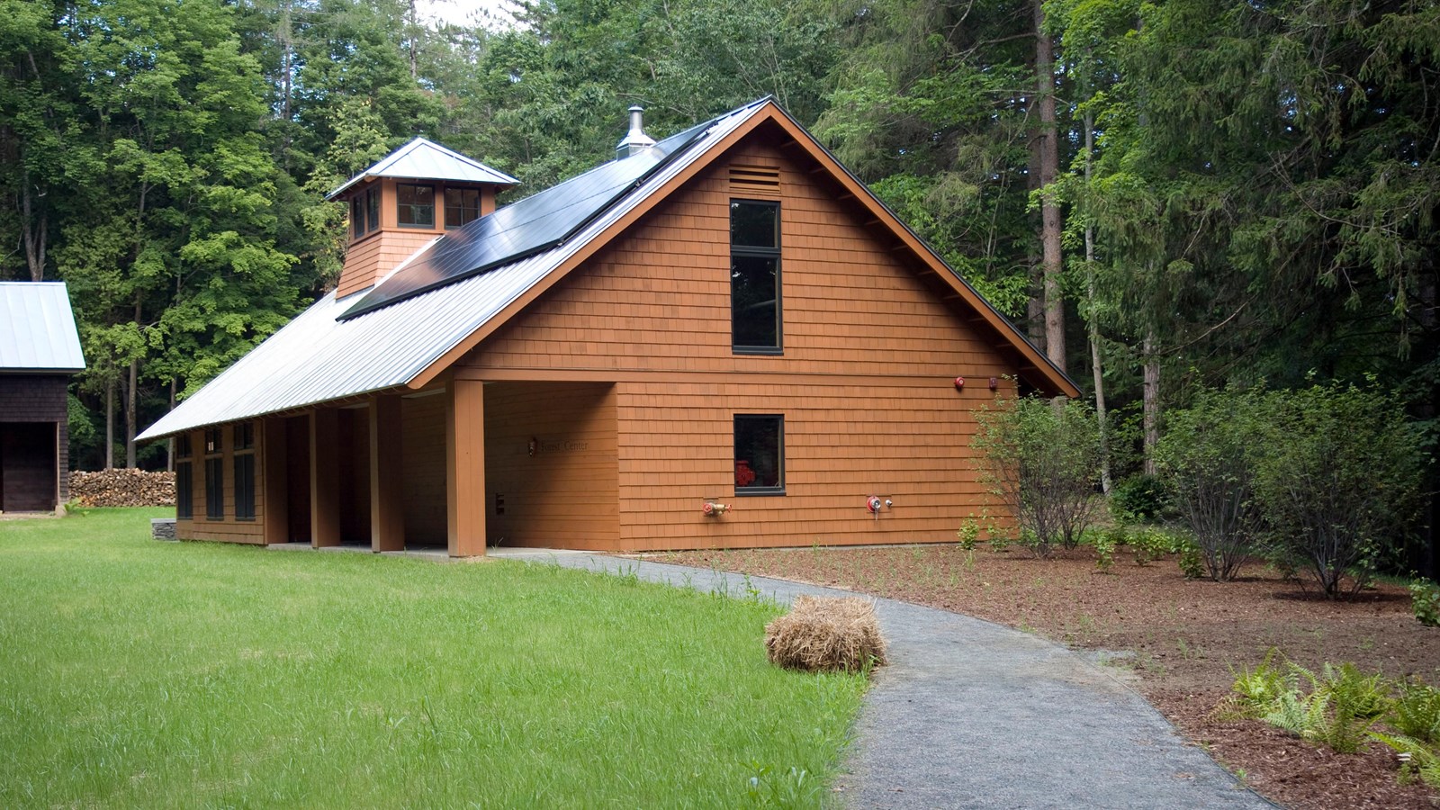 gravel path leads to wooden building with covered entrance