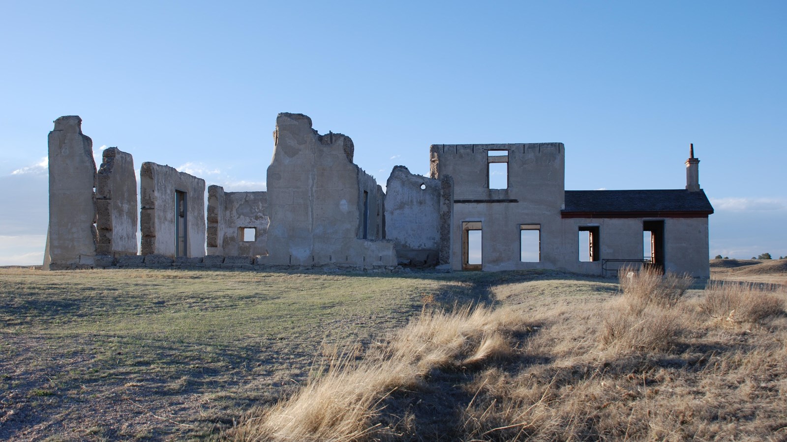 Several lime-grout walls stand together on brown grass