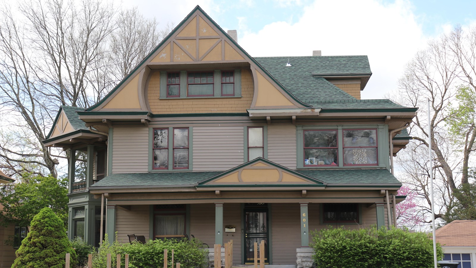 A yellow, green, and gray two and a half story Victorian home.