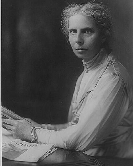 Portrait of a woman sitting at a desk, with her head slightly to the left towards her left shoulder.