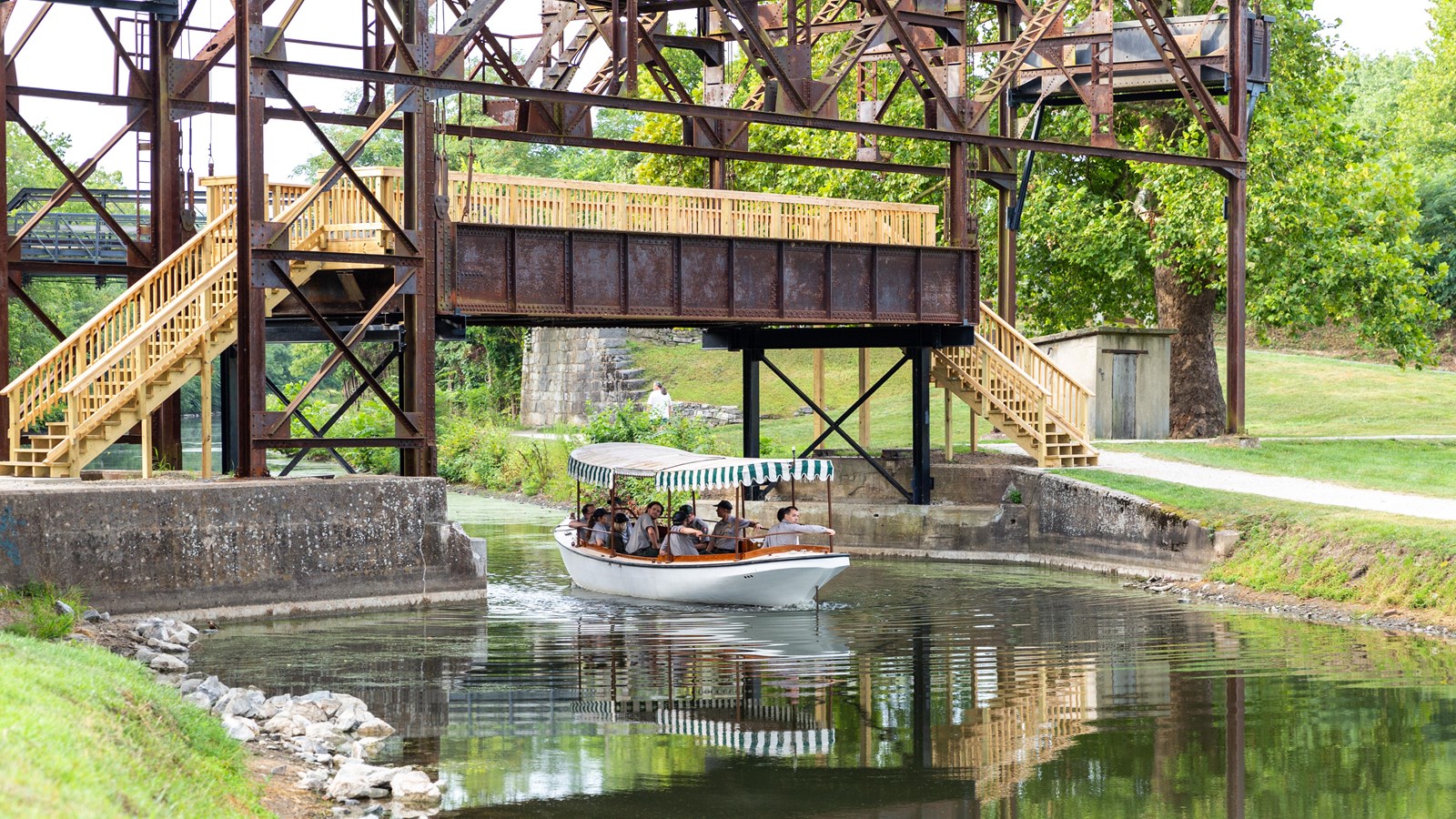 An historic metal bridge lifted in the air with a stairway across it and a boat traveling underneath