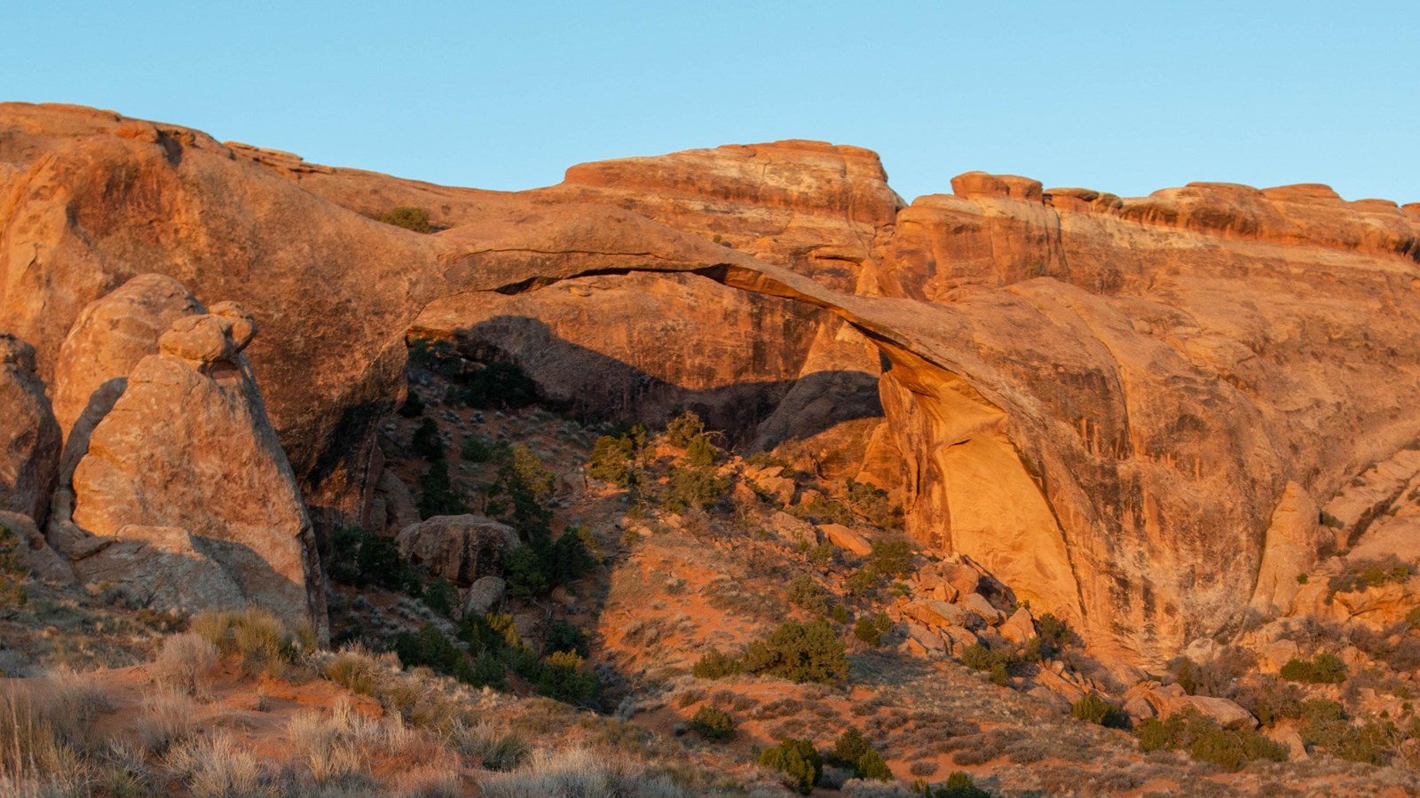 long, skinny sandstone arch in front of a sandstone wall