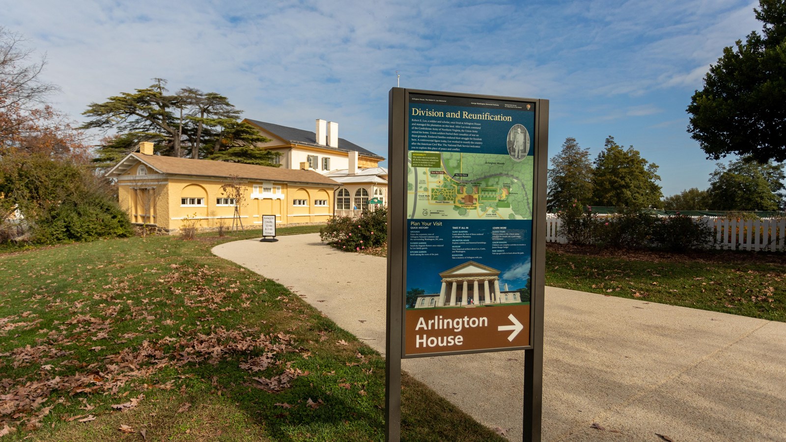 A sign indicates to follow the sidewalk on the right straight ahead to the Arlington HOuse.