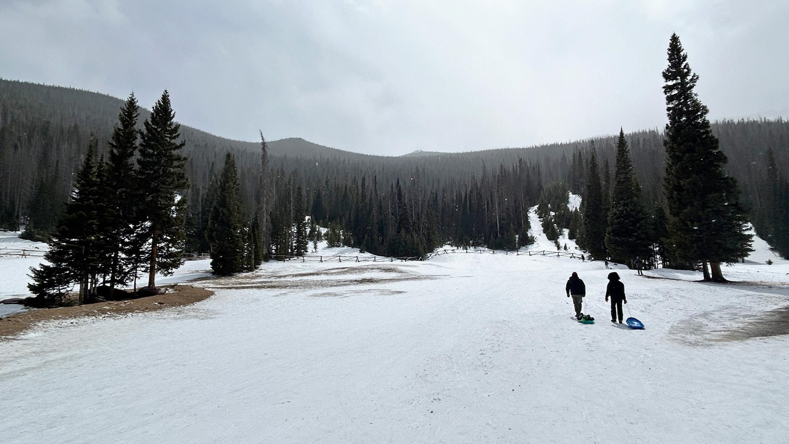 Two people are walking up the sledding hill at Hidden Valley