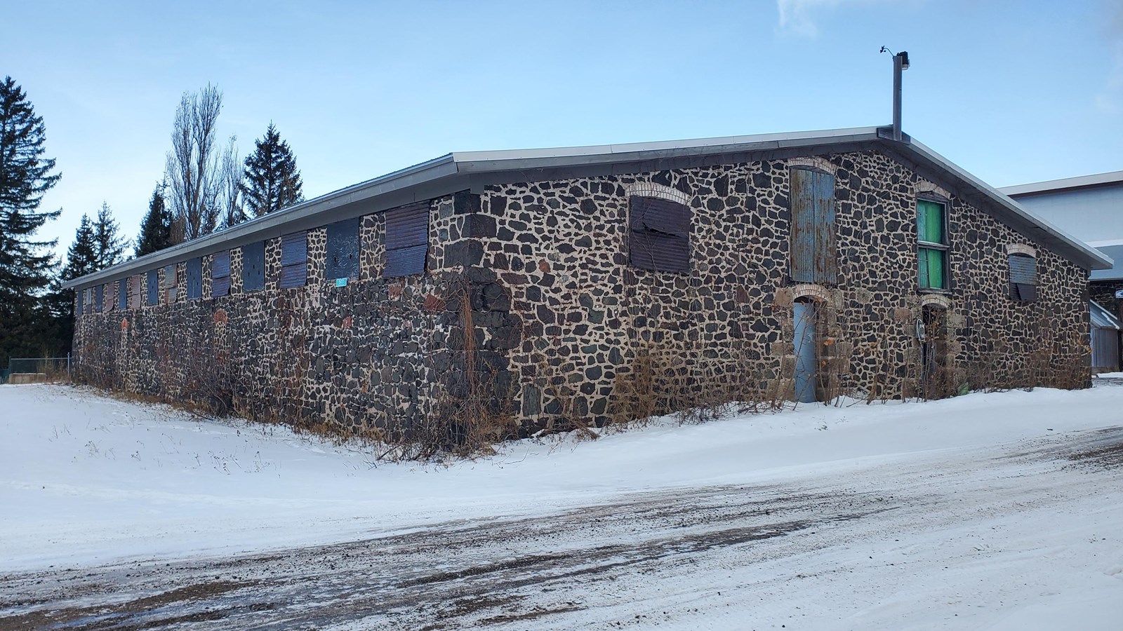 Winter scene of single-story poor-rock building with evident light-grey mortar lines.