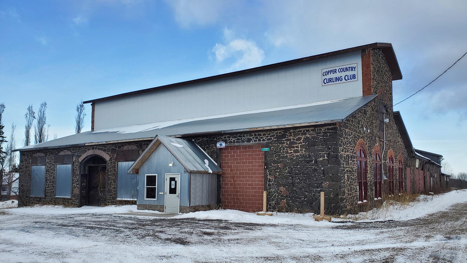 Winter scene of a poor-rock two story building with metal roofing.