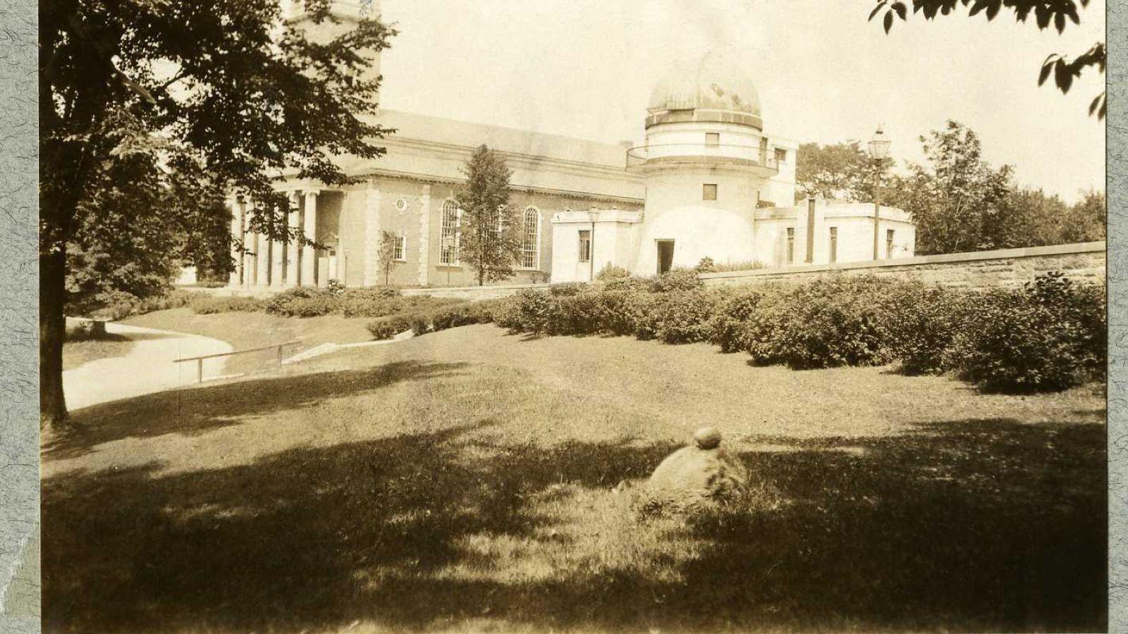 Black and white of small hill with building on top and grass and shrubs lining hill top