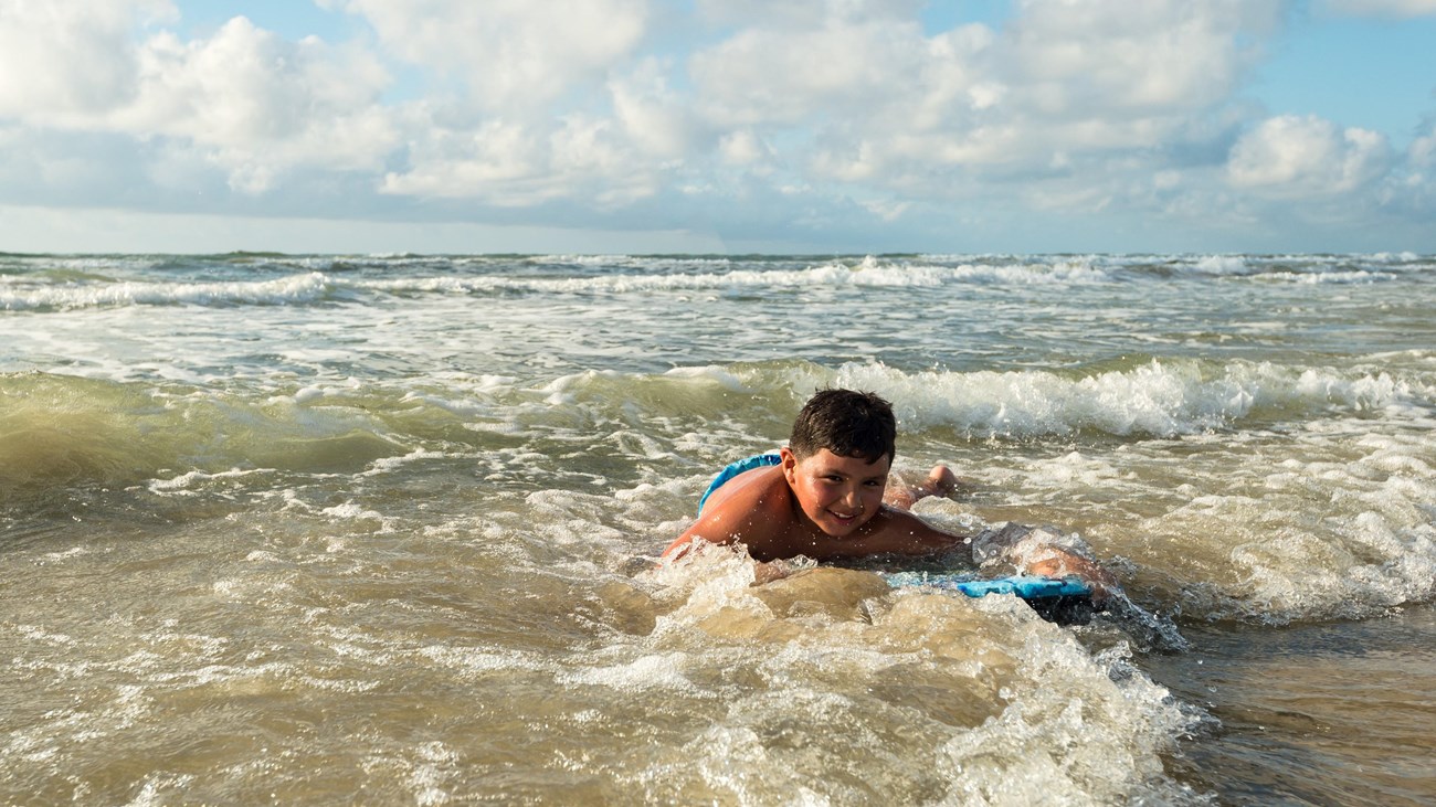 A child rides a bodyboard in the surf. 