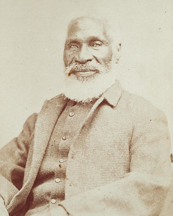 Studio portrait of Black man with full beard wearing suit
