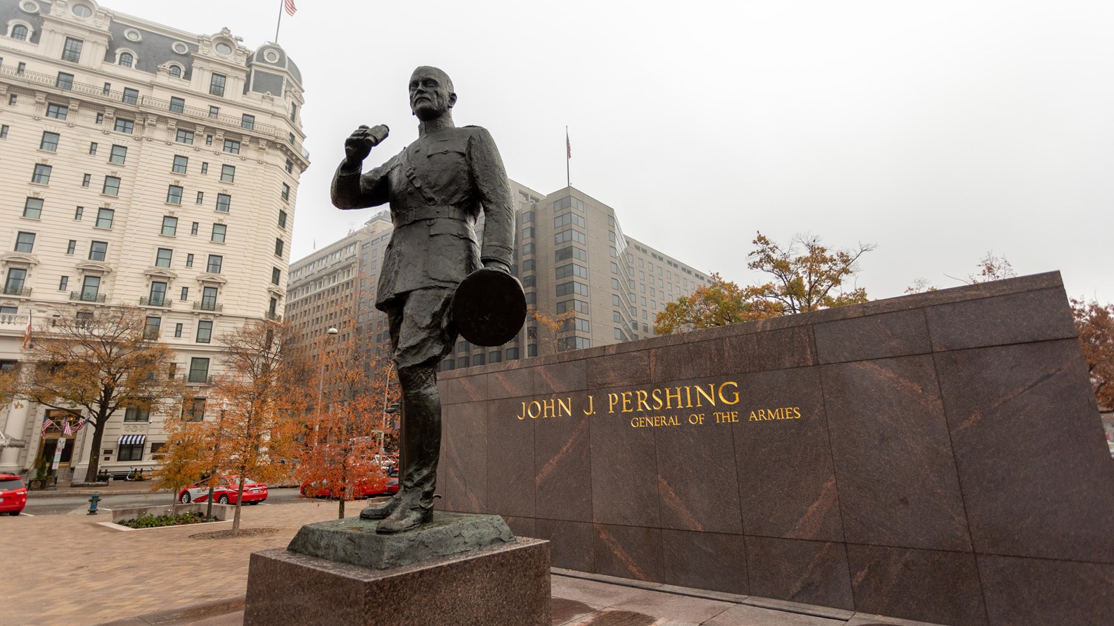 Bronze statue of General Pershing holding binoculars and his hat.