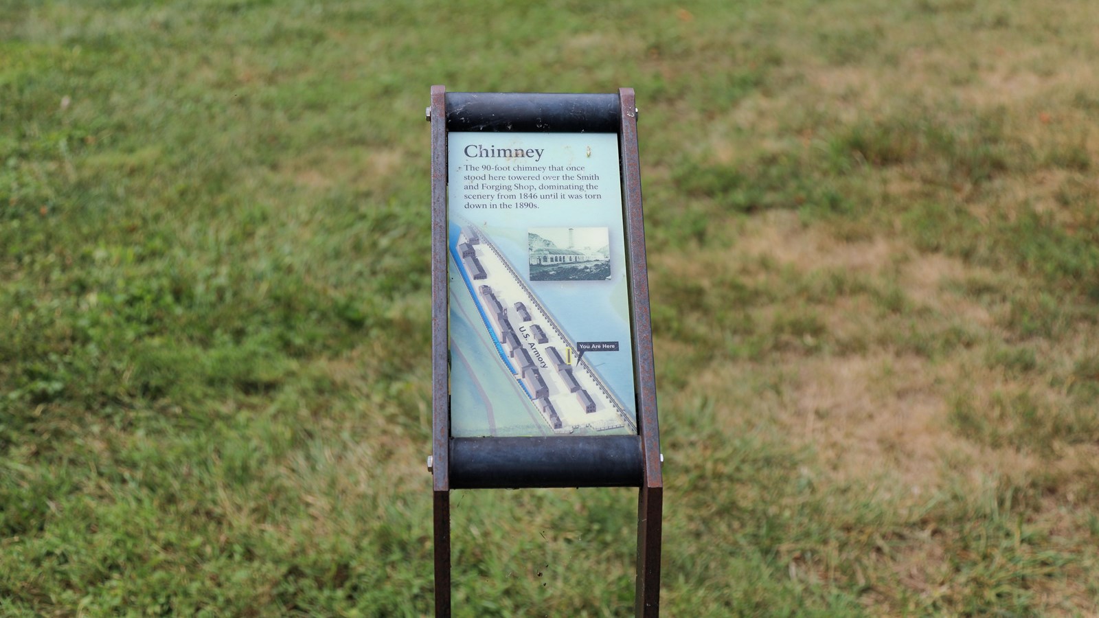An information panel in front of a grassy field. 