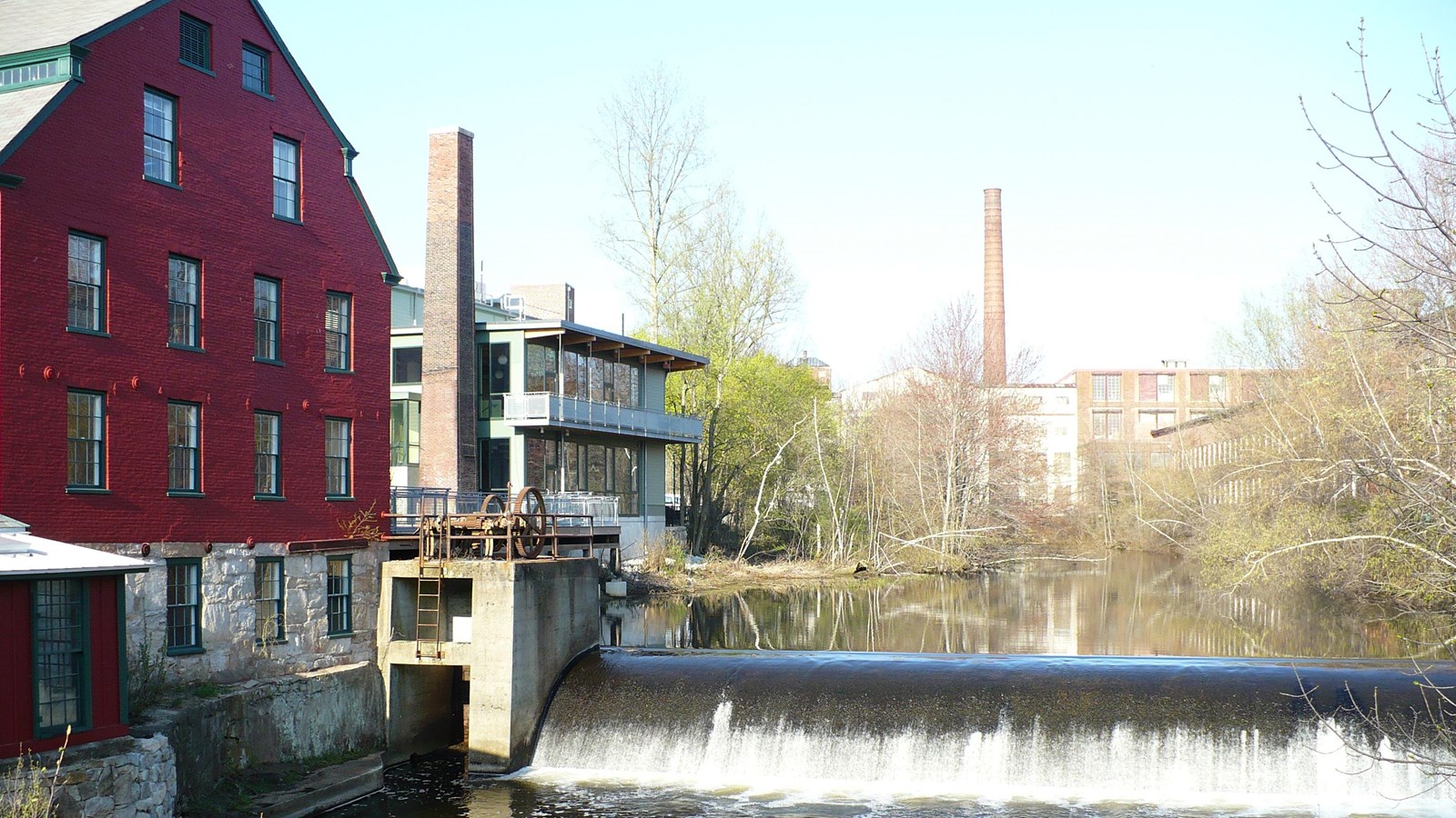 Red brick mill sits adjacent to dam and waterfall on the Mumford River
