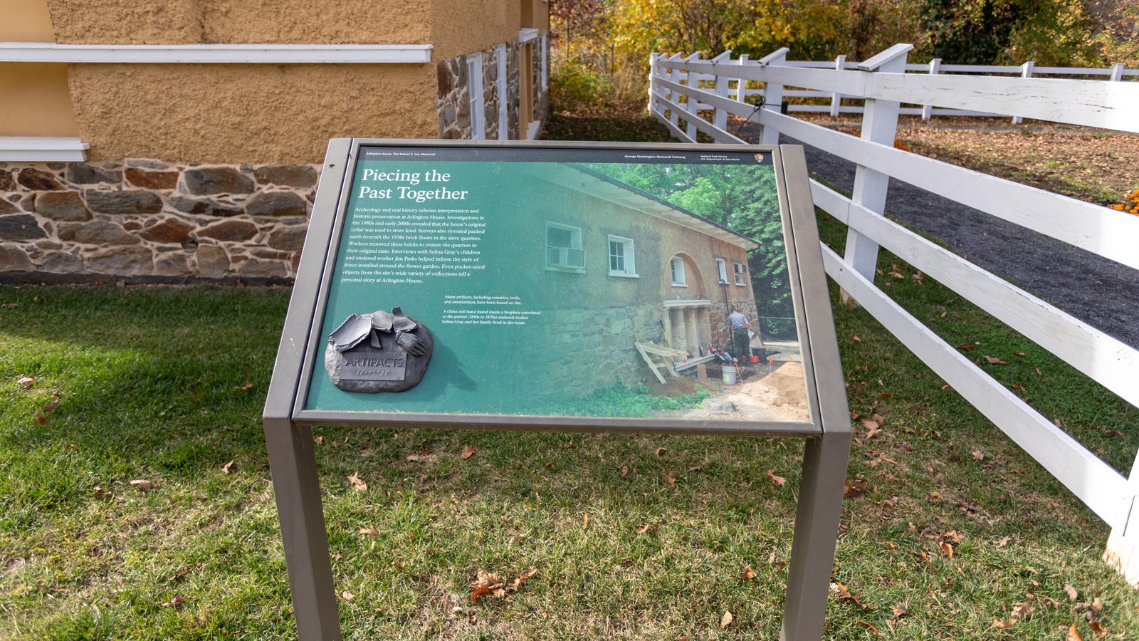 An angled wayside panel depicts potsherds and an archeologist.