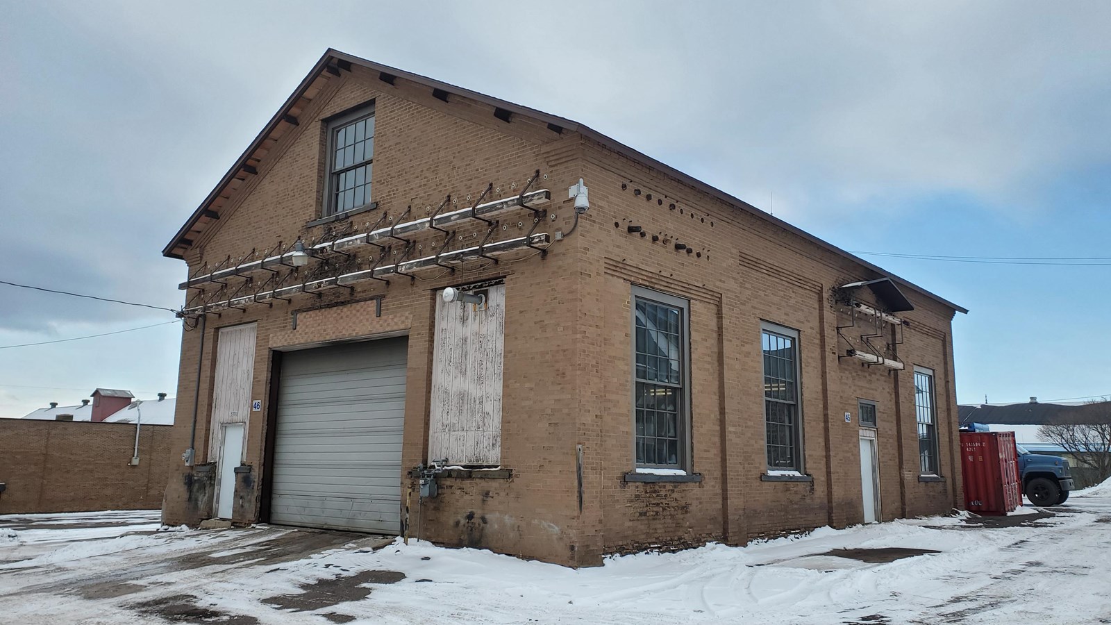 Yellow brick building with square windows, a garage door and many external electric connection bars.