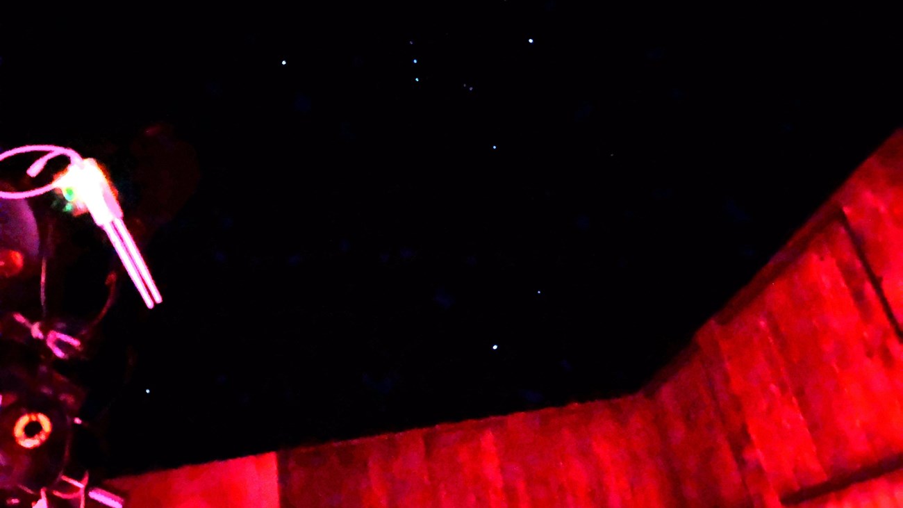 A telescope points at the sky in a wooden structure.