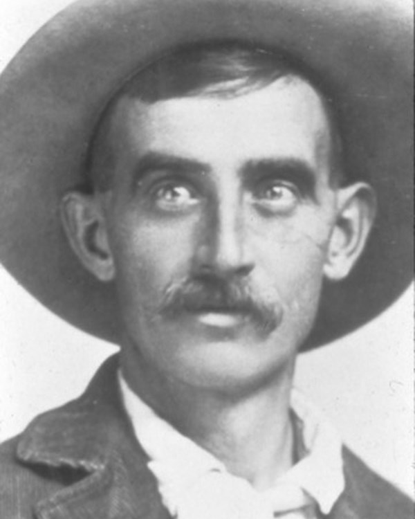 black and white, young-looking adult man with thick mustache wearing wide-brimmed hat