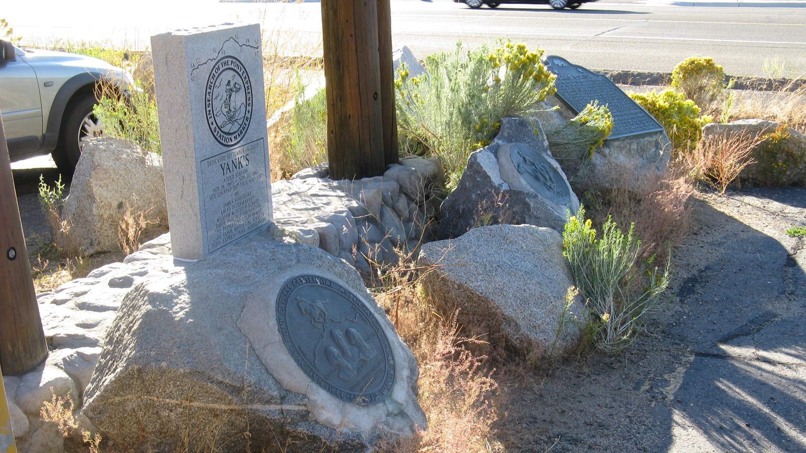 A row of four granite boulders and mounted plaques. A rectangular granite monument stands behind.