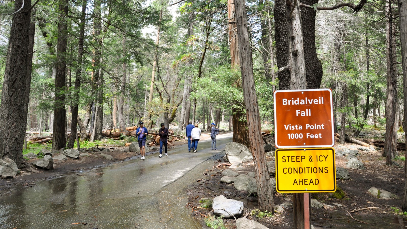 Visitors walking up the paved path from the parking area toward the fall