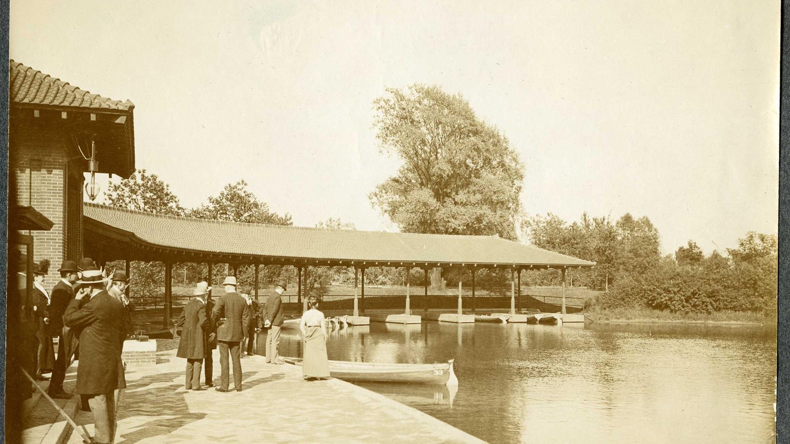 Black and white of curving docks with canoes and people standing on the docks by water