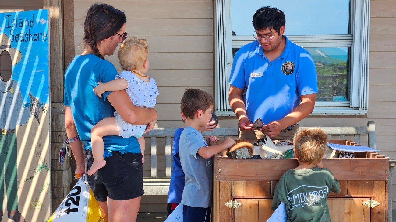 A park volunteer talks with a family about seashells. 