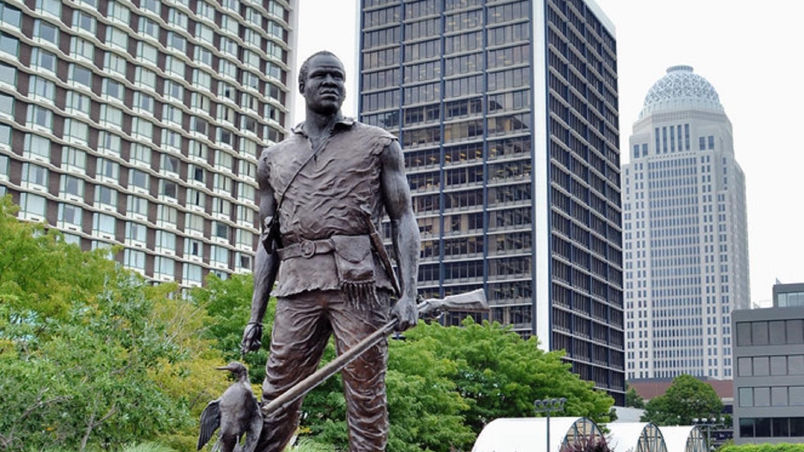 A bronze statue of a man holding a rifle and duck