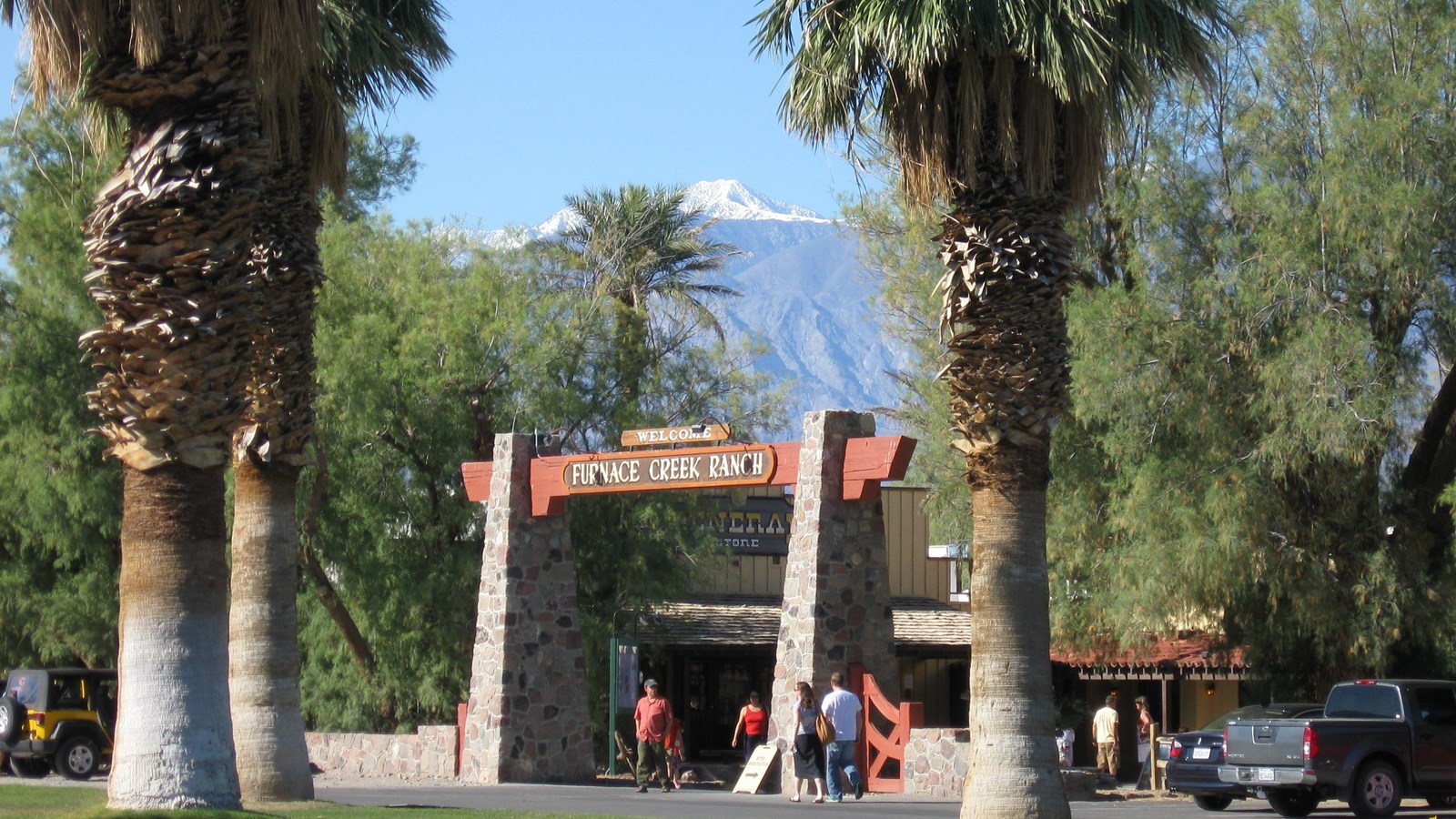 a wooden arch framed by palm trees with mountains in the distance