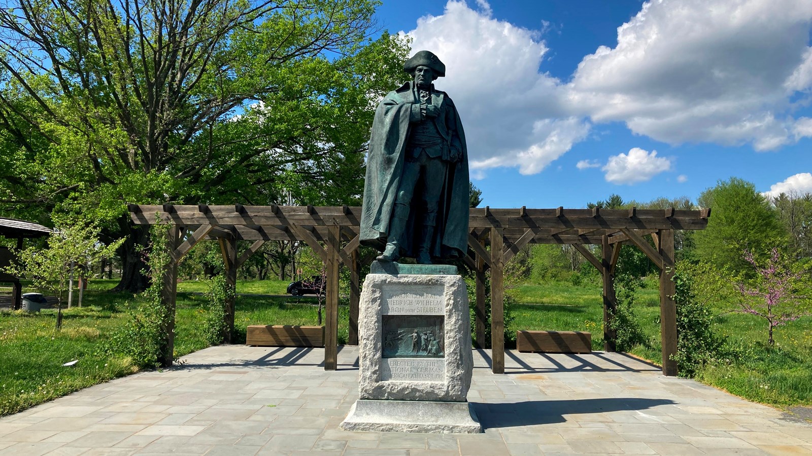 outdoors, trees, pavement, statue, bronze figure, granite base, plaque