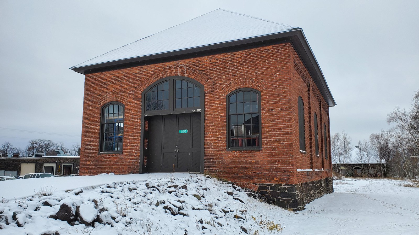 Winter scene of brick building with a ramp leading to its front door.