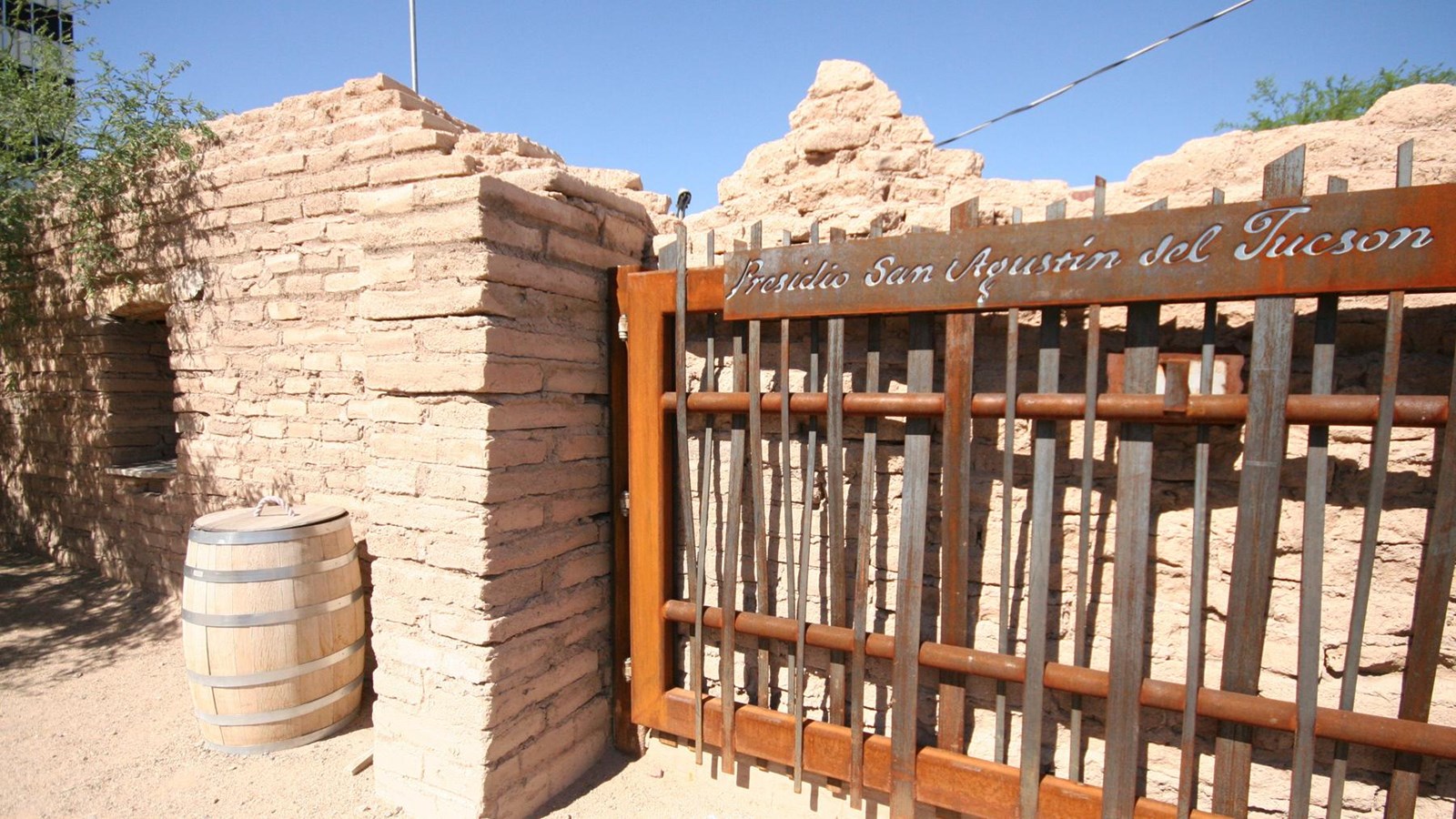 An adobe wall and rusty entrance gate with the lettering, Presidio San Agustin del Tucson