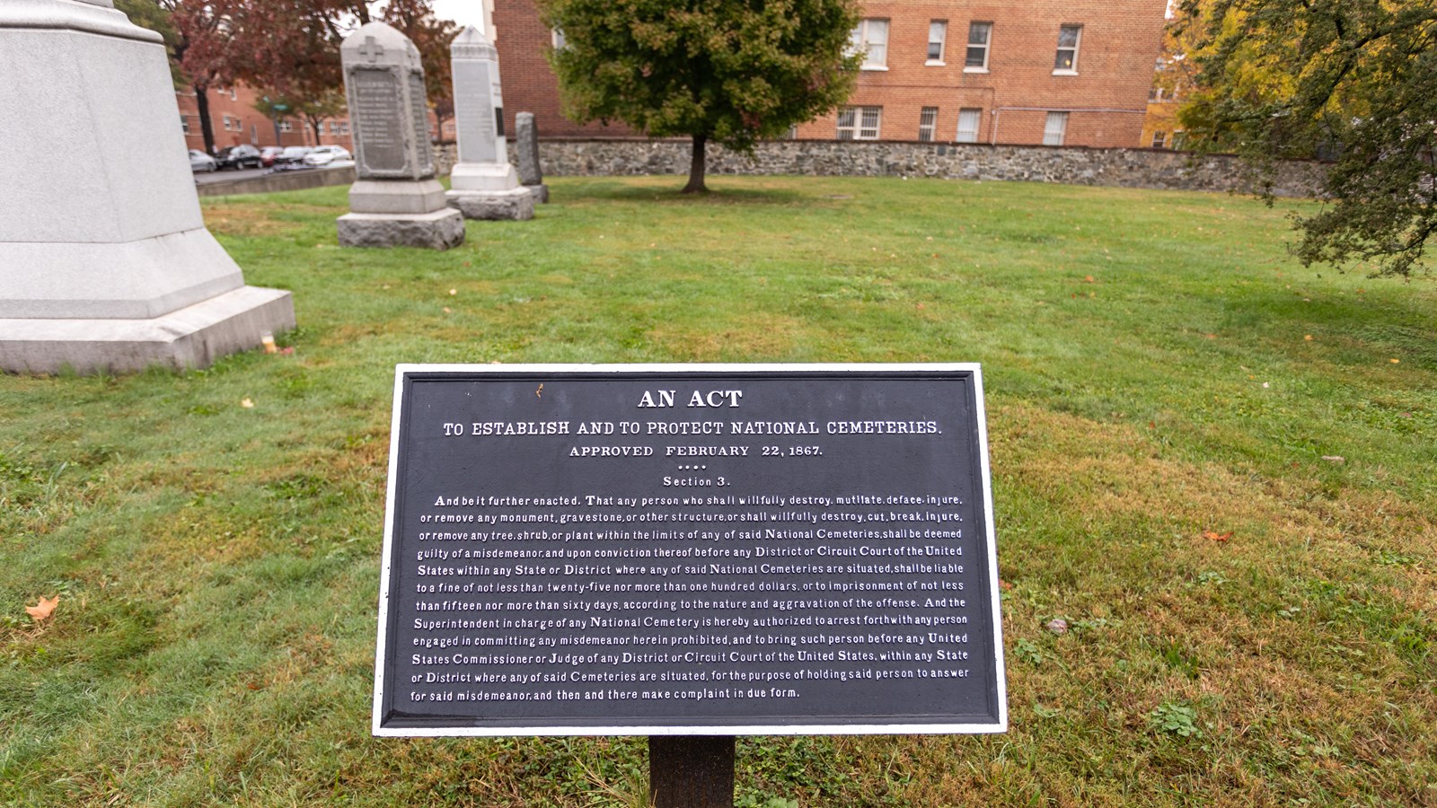 An informational panel in front of a graveyard