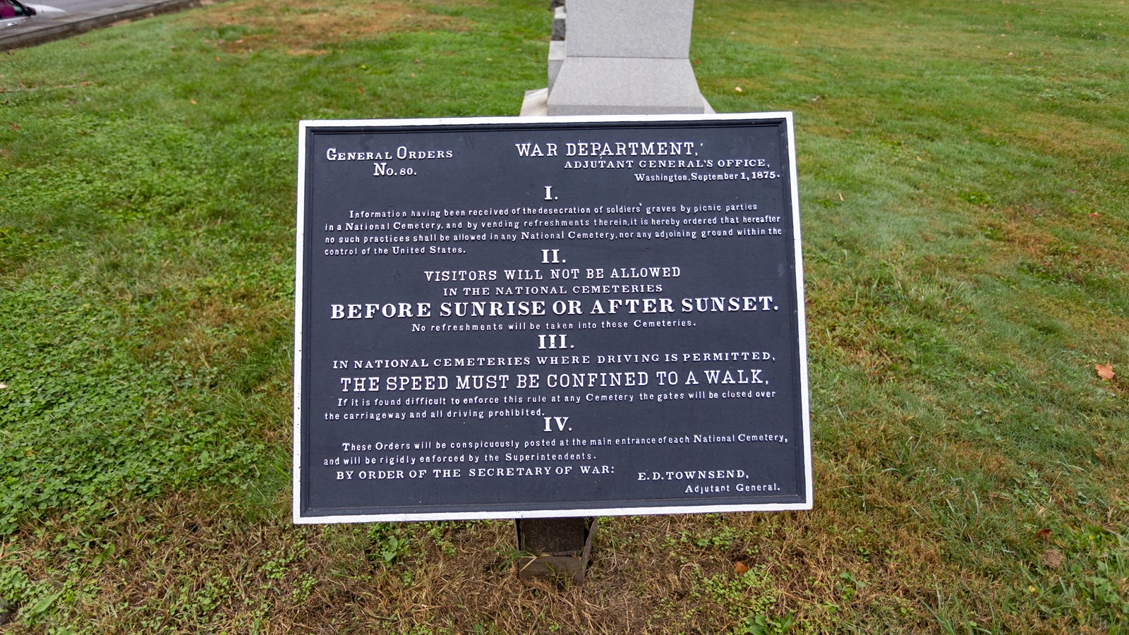 An informational plaque in front of a grassy area.