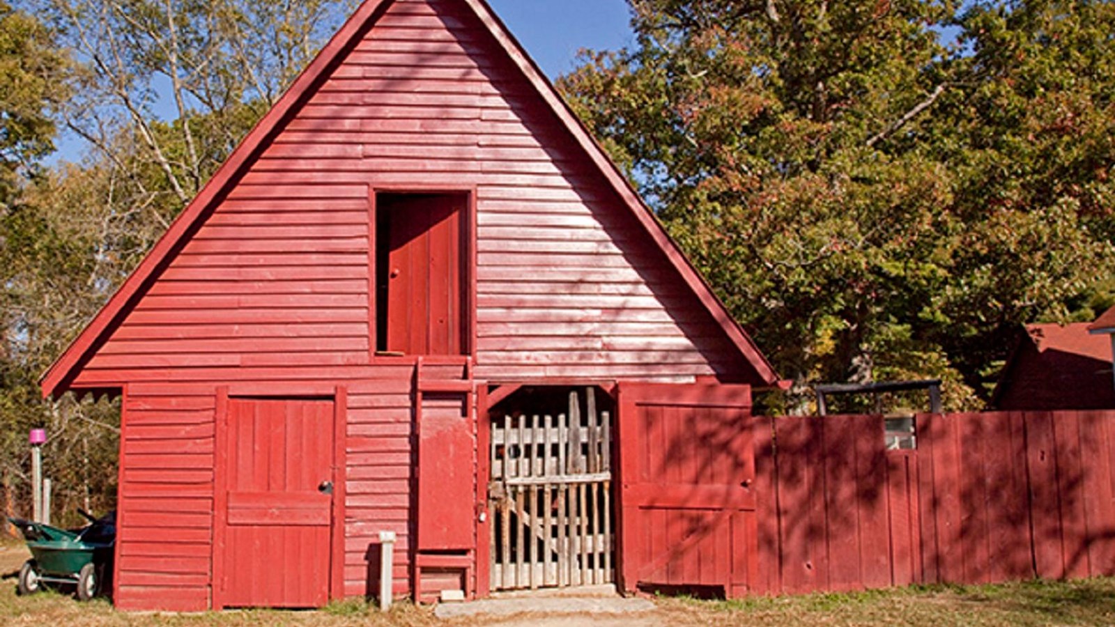 A small red barn with an A frame roof and three doors to a stable, a loft, and a side room.