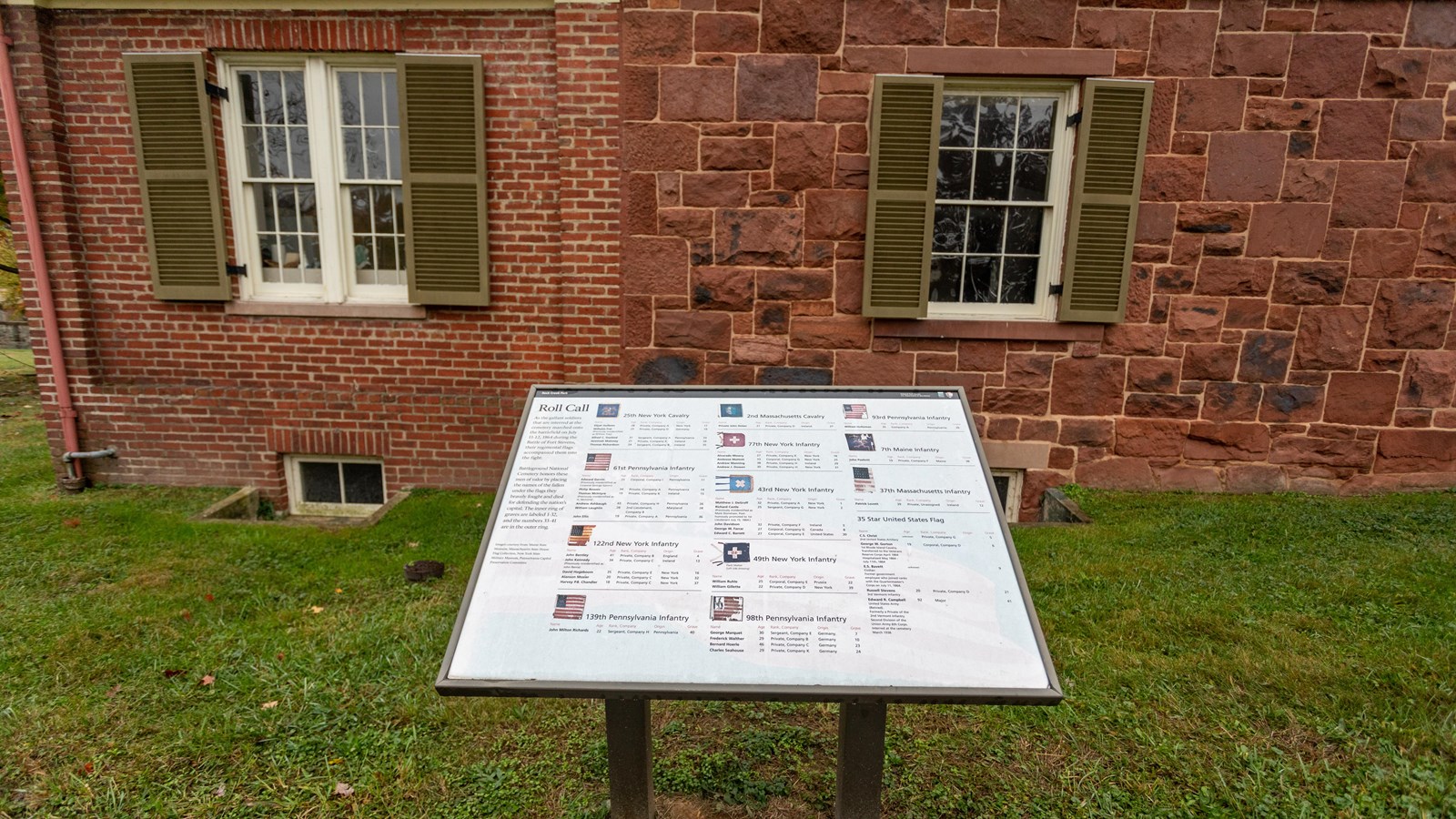 An informational panel in front of a red brick house