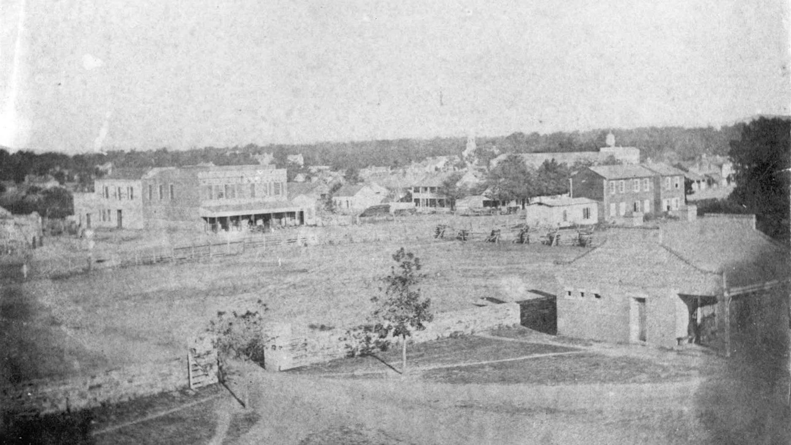 Historic photo of the guardhouse and main gate with town building in background.