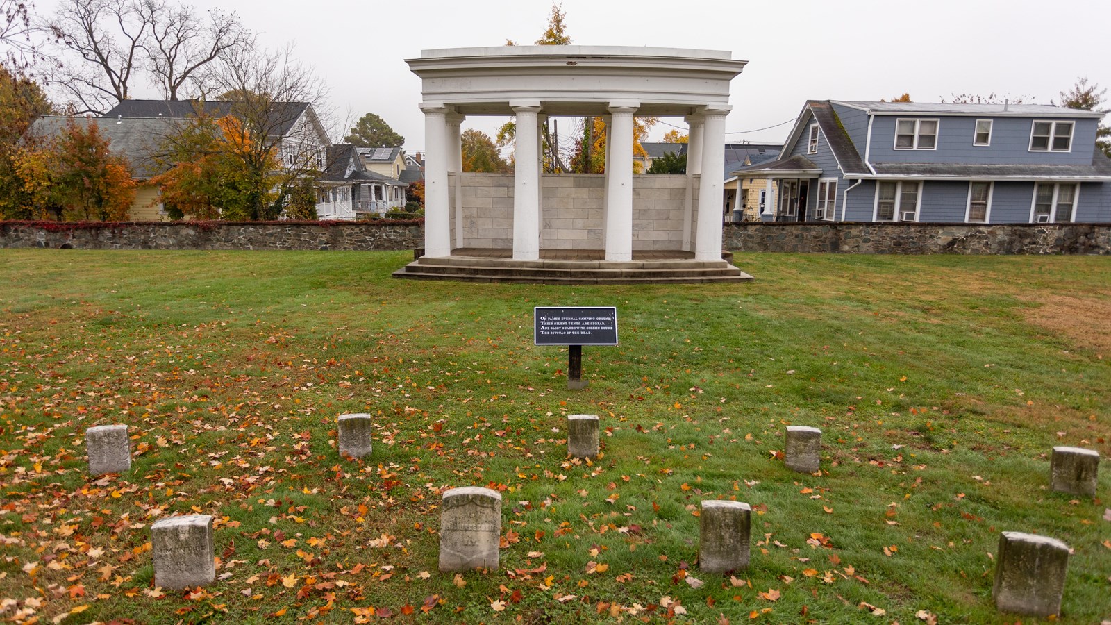 A large white pillar monument in front of a graveyard.