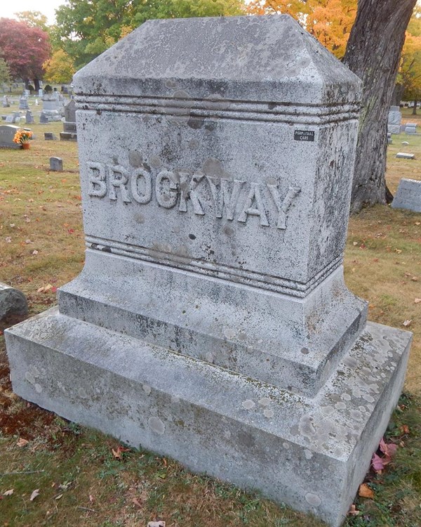 large gray stone grave marker in a sprawling cemetery in fall