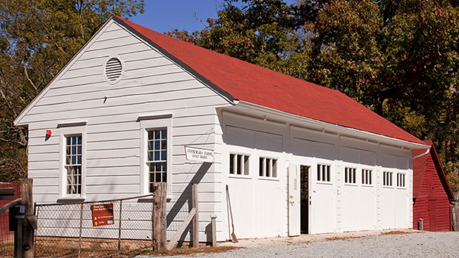 A white garage with several bays and doors houses farm equipment