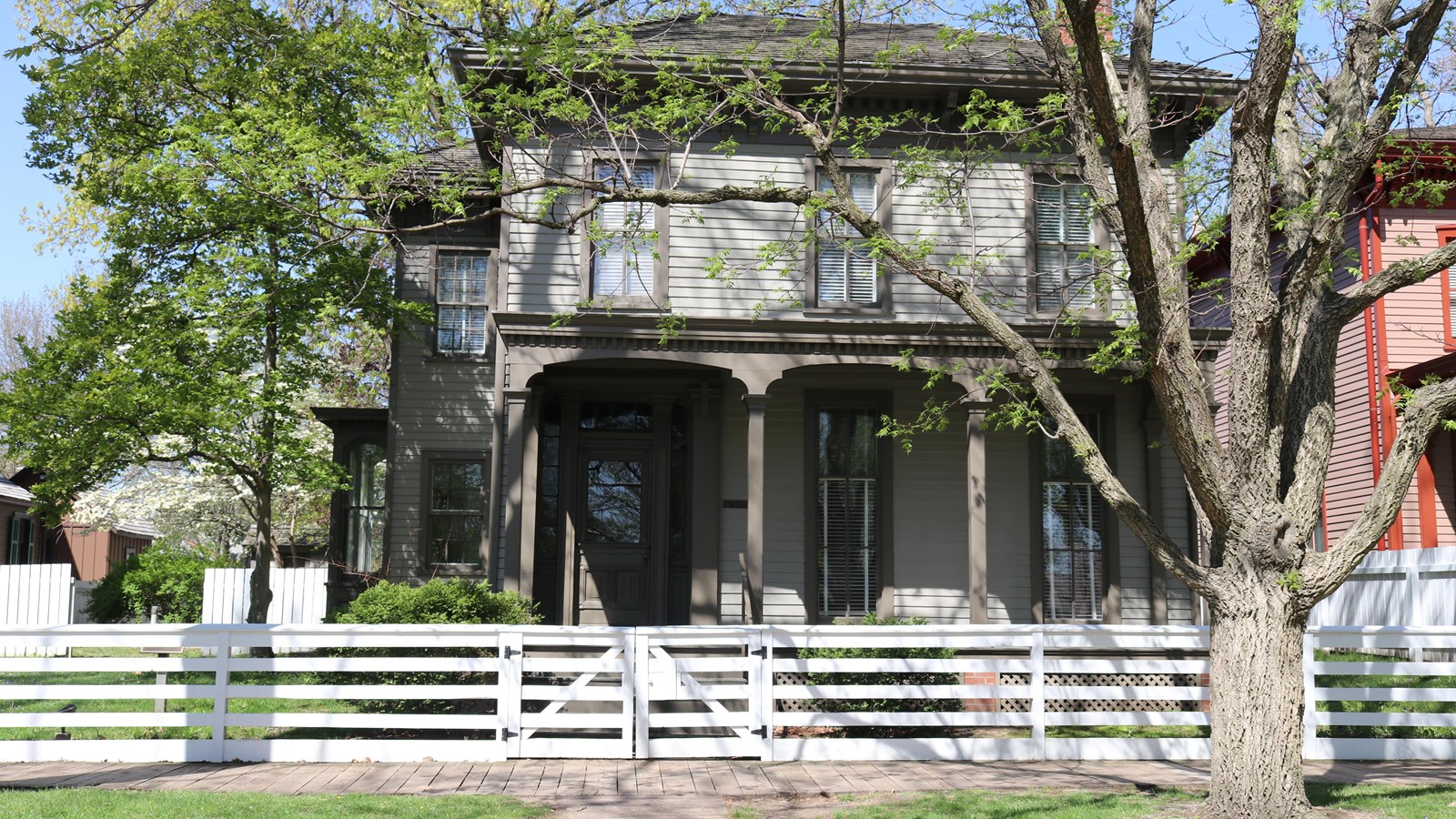 2 story light gray house with dark gray trim and front porch.