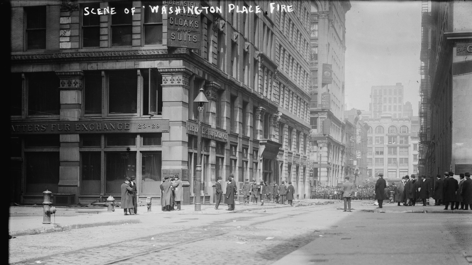 Historic photograph of crowds standing outside a city building.