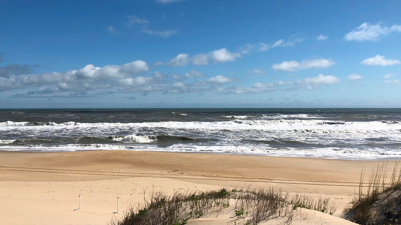 blue waves behind grass covered dune
