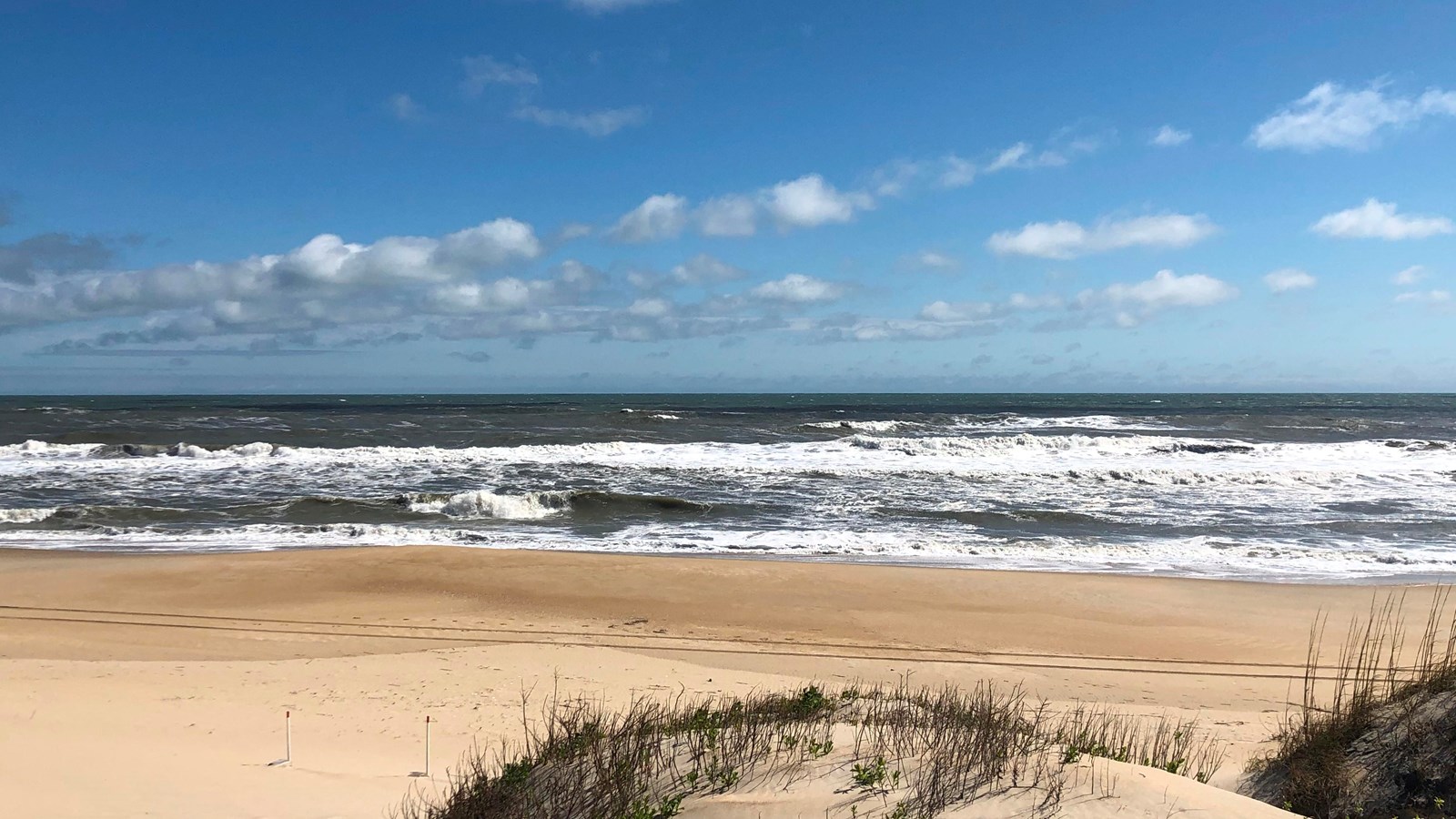 blue waves behind grass covered dune