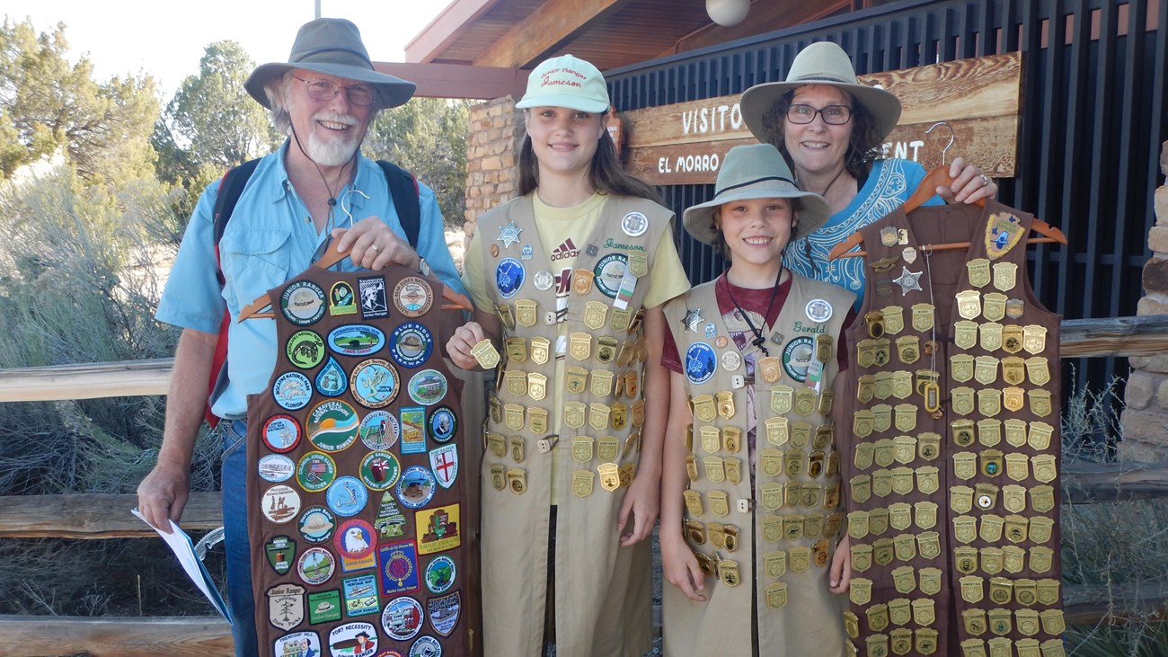 Four visitors with long vests full of golden badges.