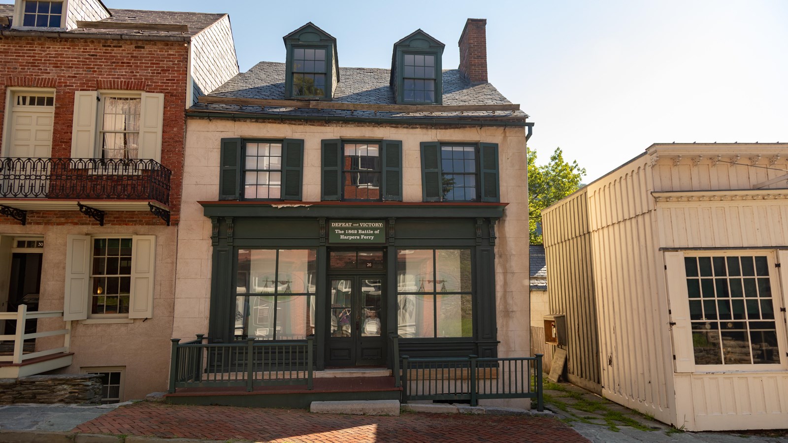 A two story house with porch and green shutters.