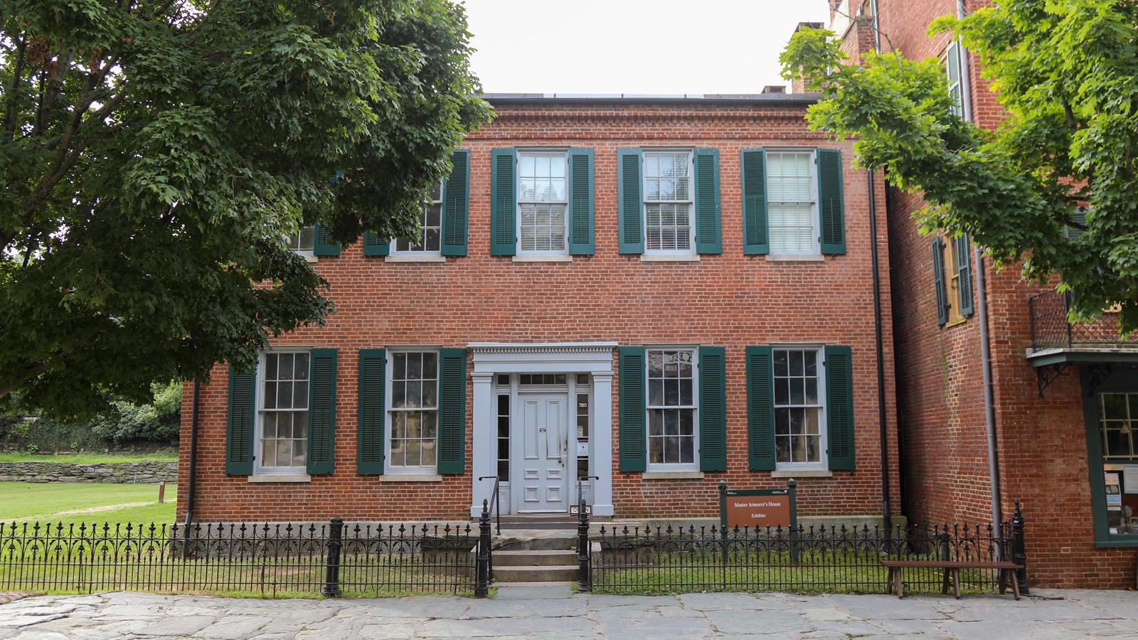 A two-story red brick building with green shutters.