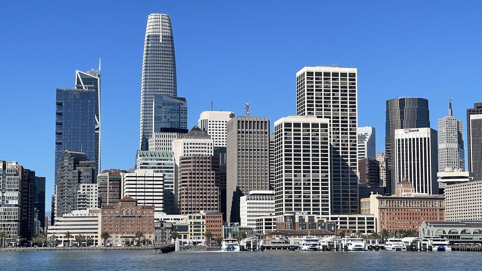 Skyscrapers loom above much smaller historical buildings at the San Francisco waterfront.