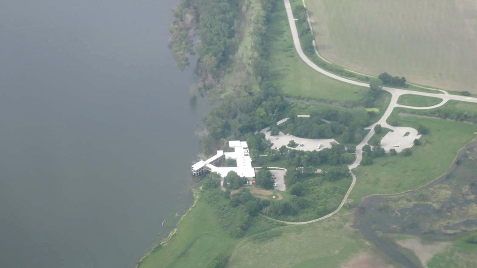 Aerial view of a white building on a grassy plain sitting along the edge of the Missouri River.