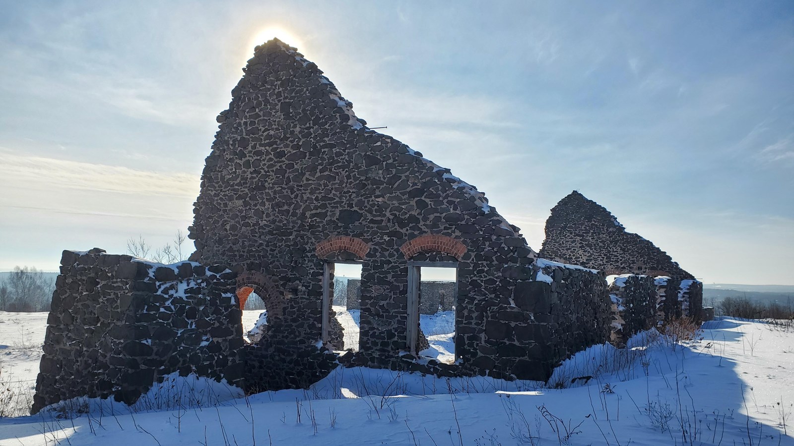 Winter scene of collapsed poor-rock building with brick arch-topped windows.