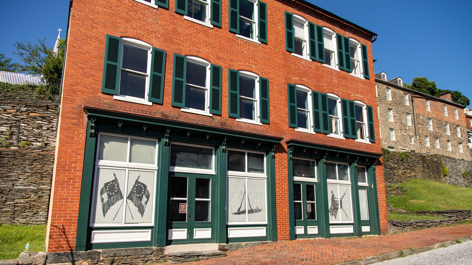 A three-story rowhouse with red brick and green trim.